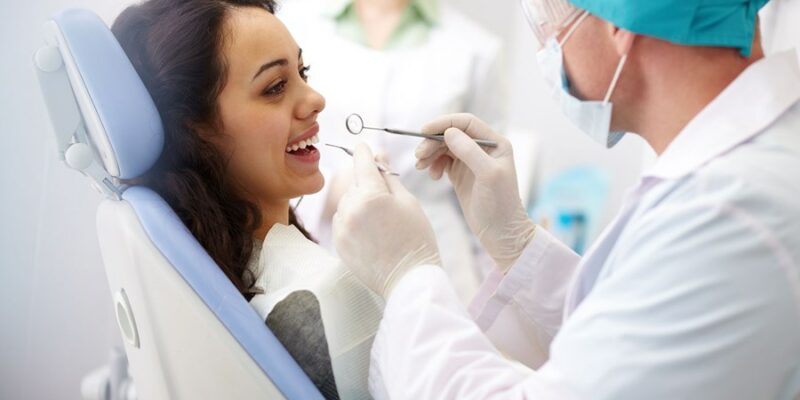 A young woman having her teeth examined by her dentist.